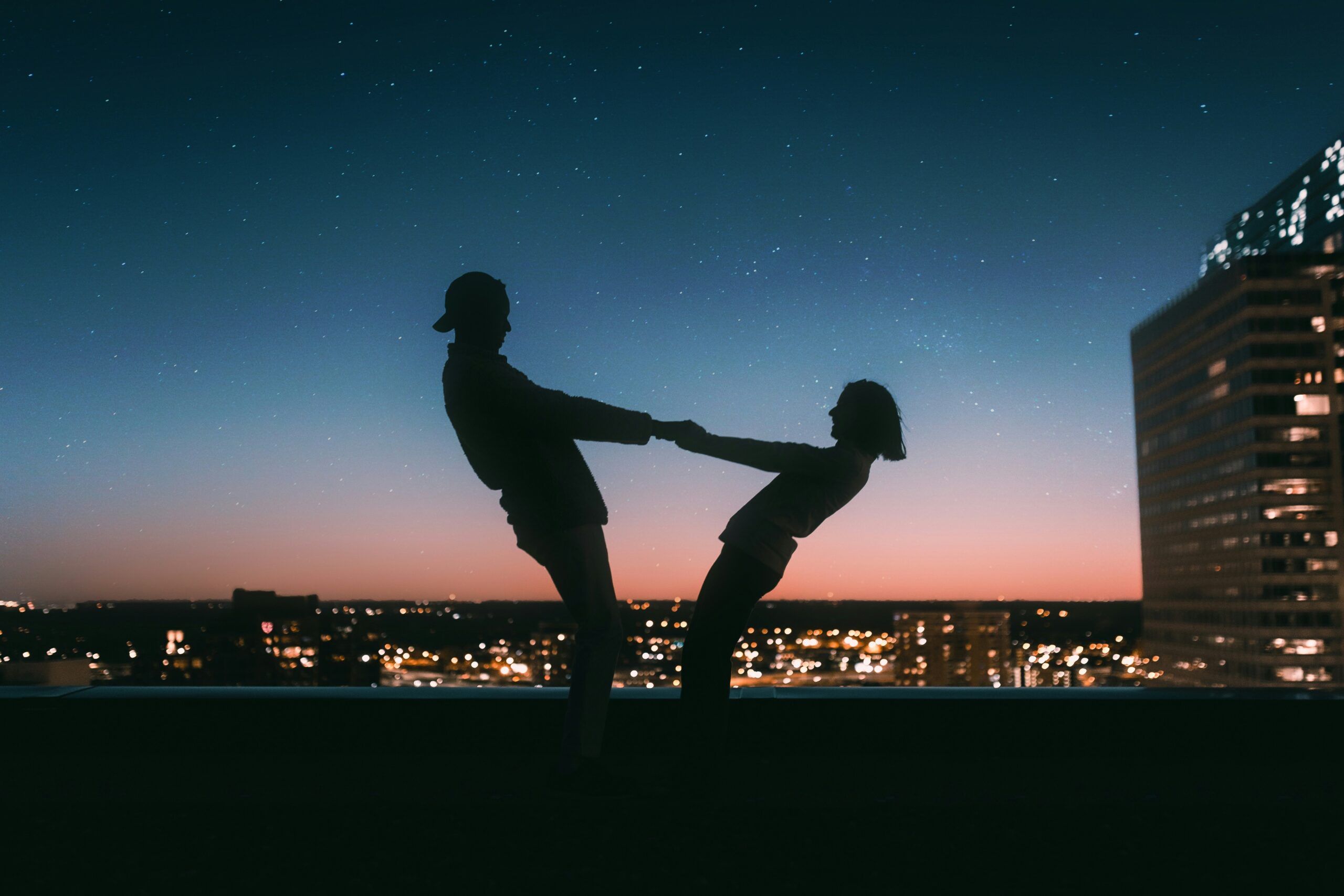 couple holding hands, carefree with sunset background.